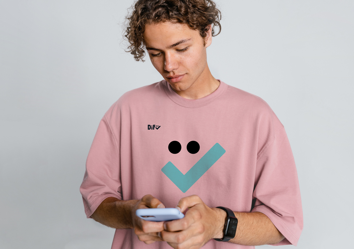 DiFü Digitalführerschein Corporate Design junger Mann mit Blick auf Smartphone in rosa Shirt mit Aufdruck Difü Logo links oben und Smiley in blau und schwarz groß mittig